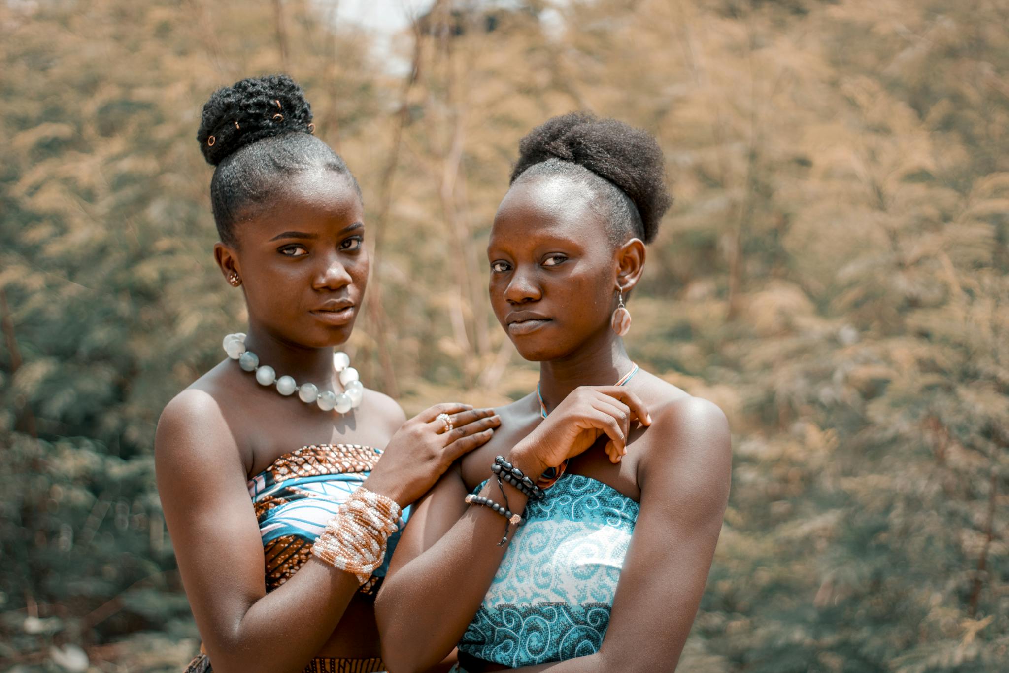 Two women in traditional clothing posing outdoors, showcasing vibrant fashion and cultural expression.